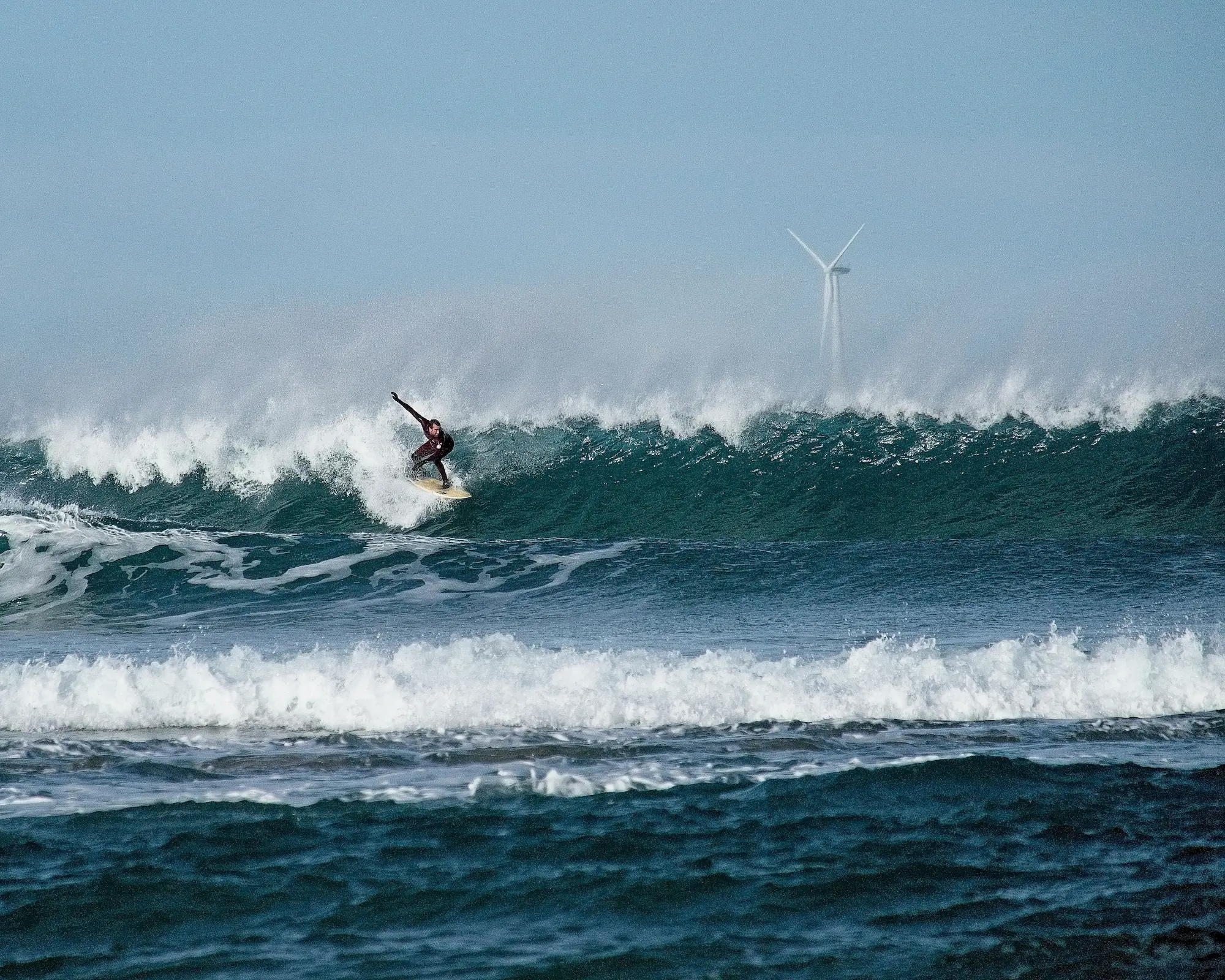 surfer with wind turbine in ocean